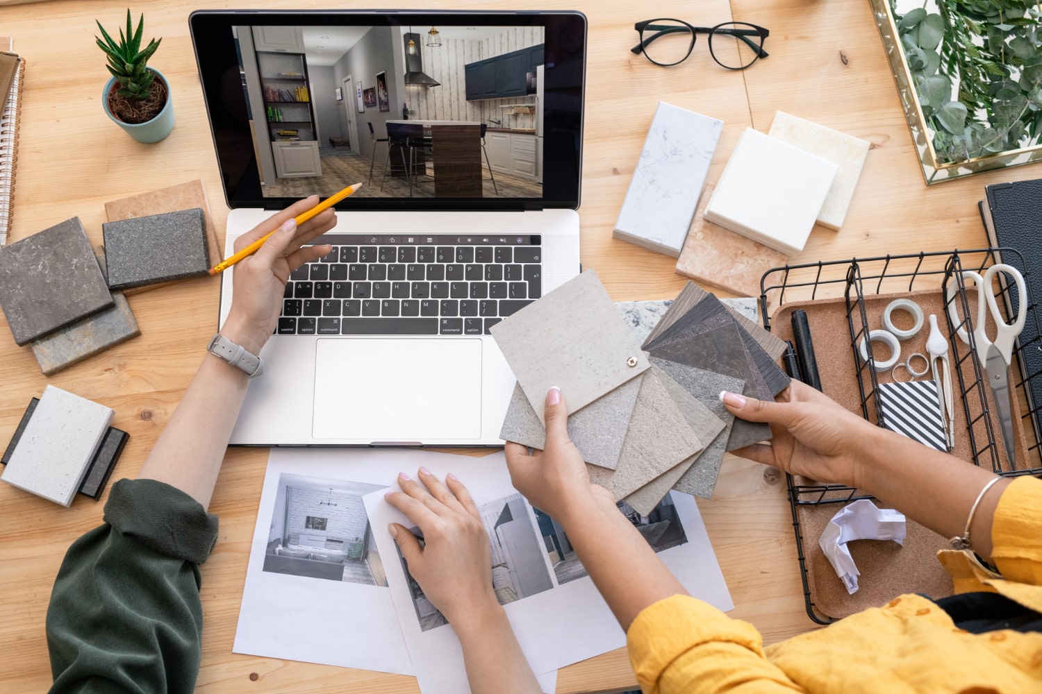 Interior designer reviewing 3D design concepts and material samples for a renovation project on a laptop.